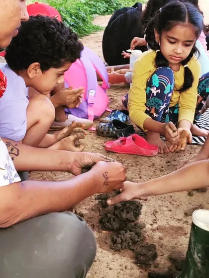 On the lake shore, children feel and examine the clay, learning about its properties before they begin to harvest it.