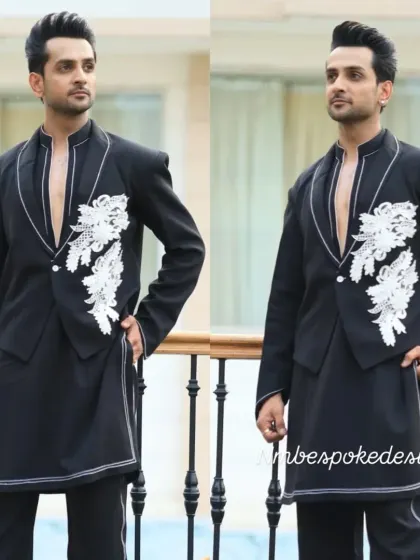 A unique fusion look combining a waistcoat and a tuxedo jacket. This black open-front piece features white floral embroidery and is layered over a long kurta for a stylish, multi-dimensional outfit.