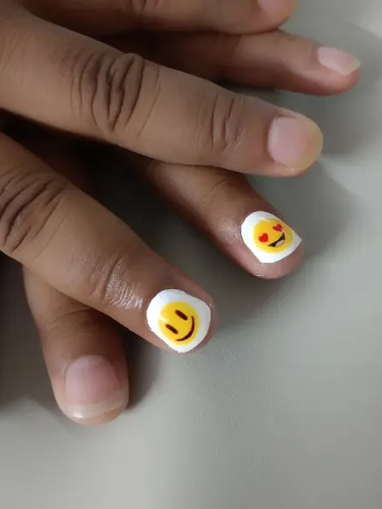 A simple and cute design for short nails, featuring hand-painted smiley face emojis.