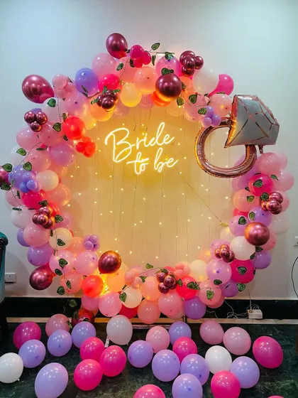 Our signature "Bride to be" ring backdrop is the perfect centerpiece for any bridal shower. This setup features a lush garland of pink, purple, and burgundy balloons, a sparkling diamond ring foil balloon, and a warm neon sign, all framed by delicate fairy lights for that magical glow.
