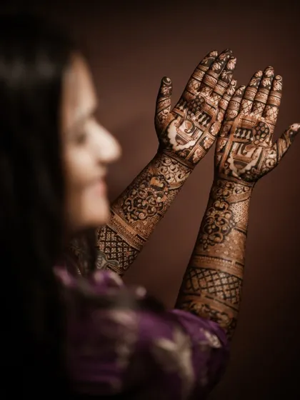 An over-the-shoulder shot of a client admiring her full-arm engagement mehndi.