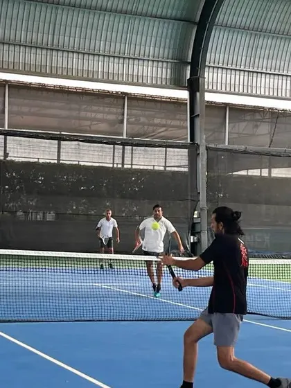An adult player hits a forehand volley at the net during a competitive doubles match. Our programs help players of all levels sharpen their skills.