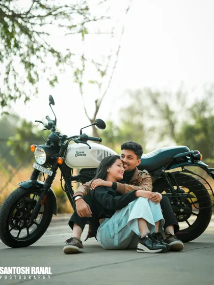 A relaxed and romantic portrait of a couple sitting with a motorcycle, perfect for a modern pre-wedding shoot.