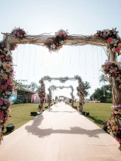A beautiful floral archway framing the path to a beachside wedding in Goa, creating a stunning entrance for guests.