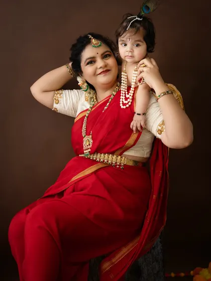 A classic portrait of a mother holding her baby, both dressed beautifully for their Janmashtami photoshoot.