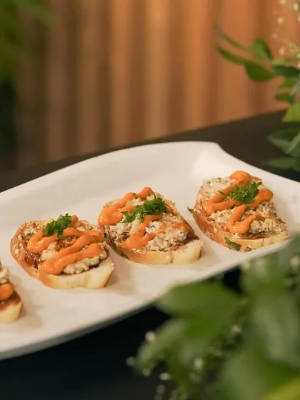 Four perfectly arranged bruschettas, topped with a savory filling and a drizzle of sauce. I focus on neat and attractive plating for all my canapés.