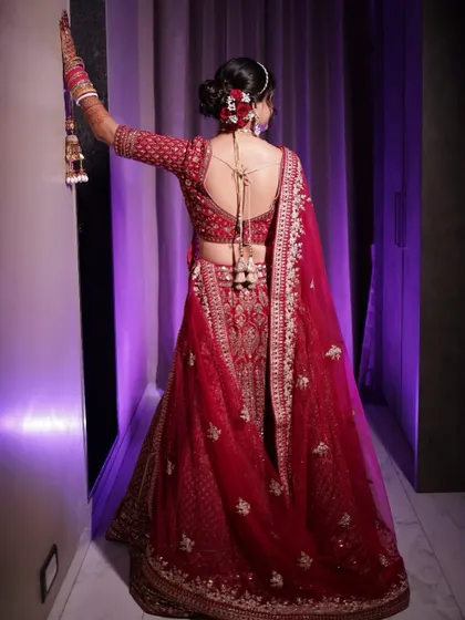 A stunning back shot of the bride, showing off her elegant bun, the back design of her blouse, and the fall of her lehenga.