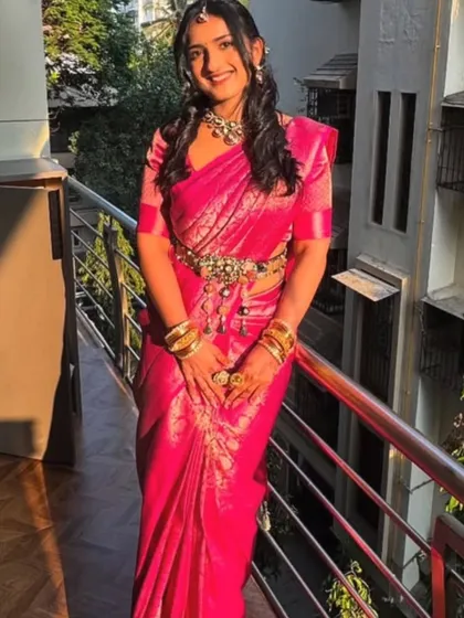 The sister in the pink Kanjivaram saree, shining in the sunlight. The drape is tailored to her body, and the intricate waist belt adds a touch of glamour to the traditional look.