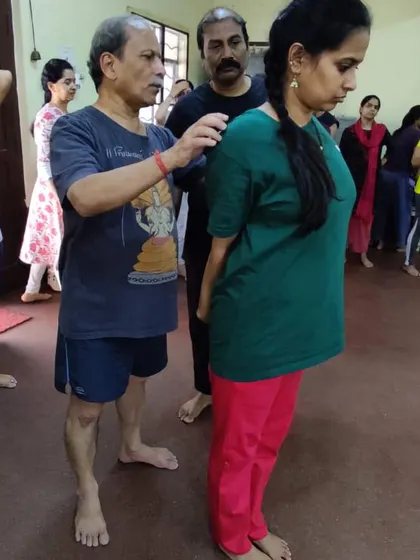Correcting a student's posture in Tadasana (Mountain Pose). The foundation of all poses begins with understanding how to stand correctly.