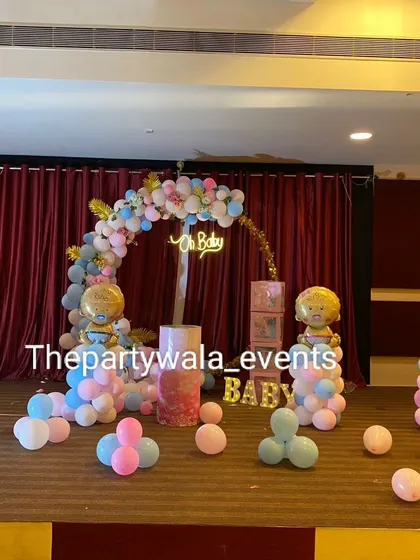 Celebrating a new arrival with a fun "Oh Baby" baby shower theme. This stage setup uses a half-arch of pink and blue balloons, cute baby-themed foil balloons, and pedestals for gifts or a cake, making it perfect for a gender reveal party.