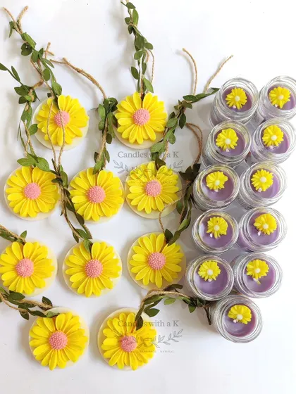 A set of mini jar candles with flower toppers and daisy soy wax sachets, created for a baby shower in Thane.