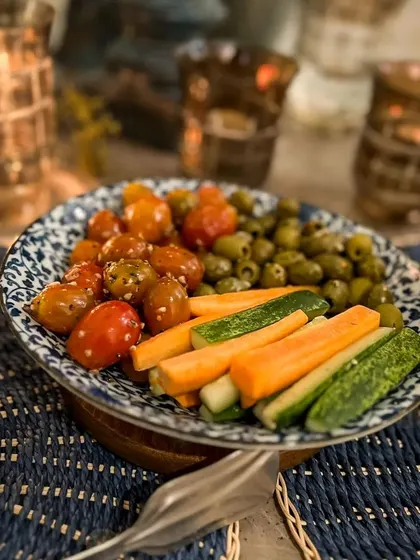 A simple yet elegant bowl of marinated olives and cherry tomatoes with fresh vegetable sticks. This classic Mediterranean appetizer is perfect for a light and healthy start to a meal.