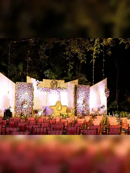 An evening view of a grand wedding stage at Sumatra Wedding Venue in JP Nagar, Bengaluru. The lighting design highlights the floral textures and creates a warm, inviting atmosphere for the celebration.