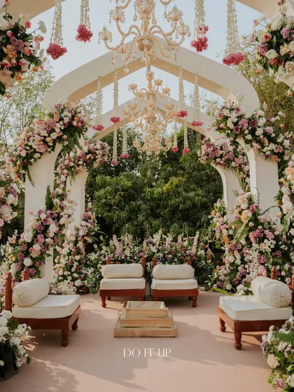 The mandap design for this Jaipur wedding featured a series of arches covered in pink and white flowers, with chandeliers and floral tassels hanging from the center. The low, traditional seating kept the focus on the couple and the rituals.