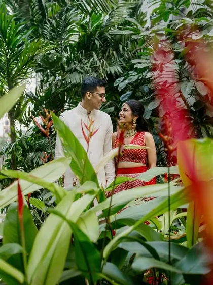 A creative portrait shot through lush green foliage. This framing technique adds depth and a sense of intimacy, as if we're peeking into a private moment.