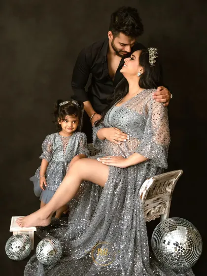 A glamorous maternity portrait with the whole family. The mother and daughter wear matching sparkling silver dresses, creating a dazzling and cohesive look.