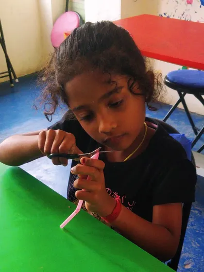 A close-up of a child carefully cutting straws, a key step in building our simple flying machines. This hones fine motor skills.