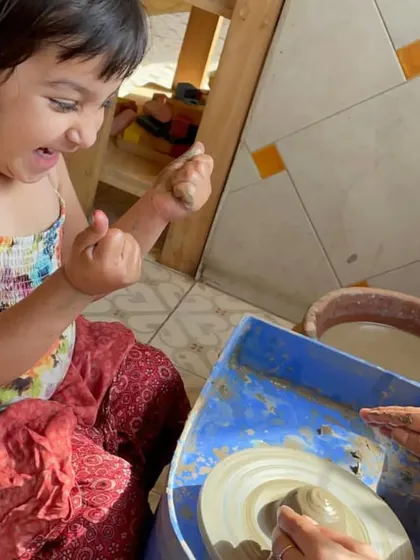 The thrill of seeing the clay take shape. This girl's expression of pure joy is a common sight in our pottery corner.