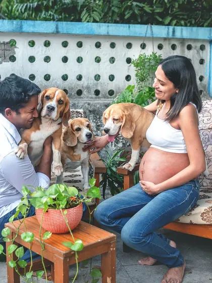 An expecting couple enjoys a relaxed moment on their home patio with their three Beagle dogs. This image shows how I lovingly include furry family members to capture the complete picture of your life.