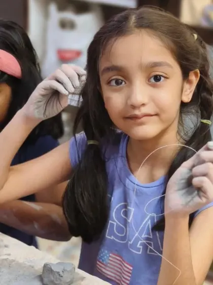 A young student carefully uses a wire tool to cut her clay. We teach children how to safely use basic pottery tools to bring their ideas to life.