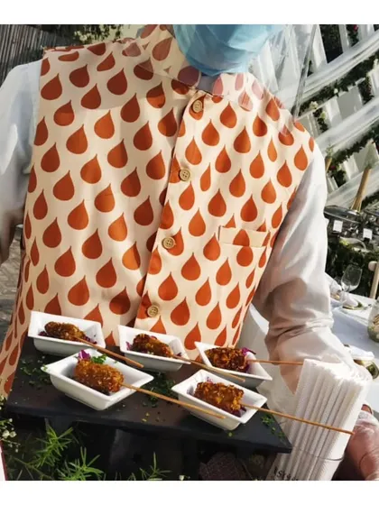 A server in our signature vest holds a tray of skewered appetizers, showcasing our professional and stylish pass-around service.