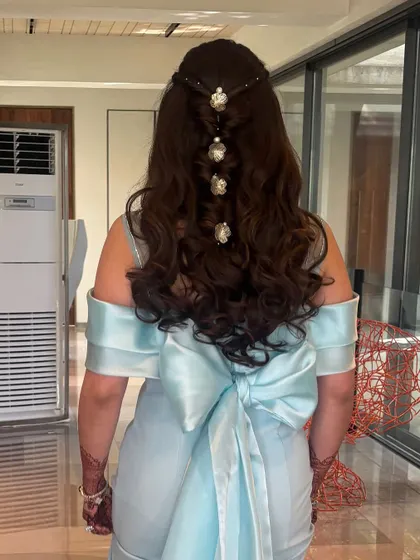 A beautiful half-up hairstyle for an engagement party. This look features a twisted bubble braid effect down the back, adorned with delicate floral accessories.