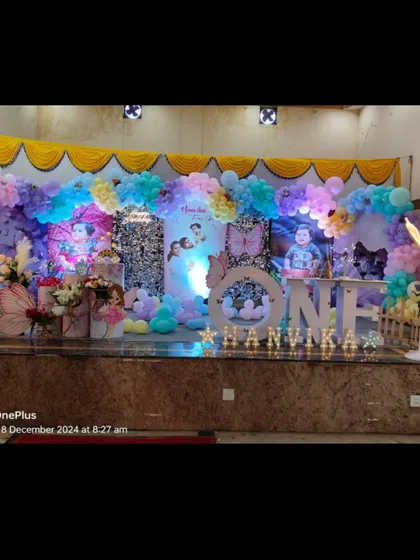 A grand butterfly-themed stage for Hanvika's first birthday. The setup uses pastel balloons, large butterfly props, and a sequin backdrop to create a dreamy effect.