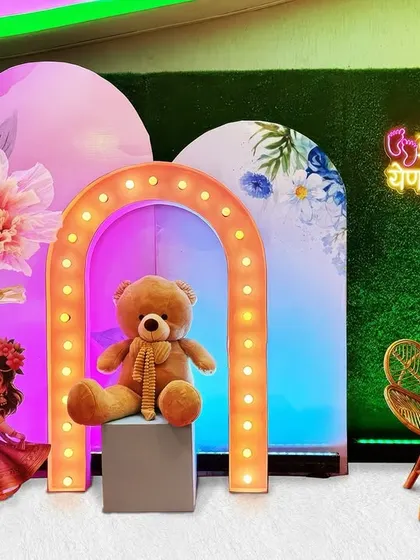 A beautiful celebration does not need a huge budget. This is an example of a compact and affordable baby shower setup that combines a cute teddy bear, a lighted arch, and colorful backdrops for a joyful and memorable event.