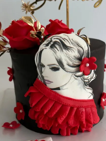 A close-up of the intricate, hand-drawn portrait on the elegant black and red cake.
