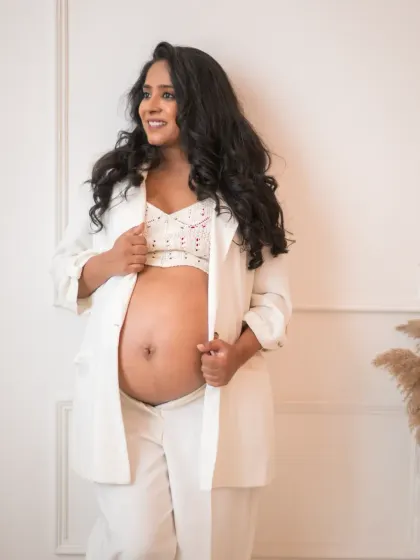 A modern and chic maternity look, featuring a white blazer and crop top that beautifully showcases her baby bump. This portrait is for the mom who wants to celebrate her pregnancy with confidence and style.