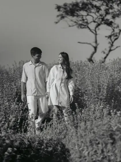 A serene walk through a field of flowers. In black and white, the texture of the plants and the quiet companionship of the couple become the central focus.