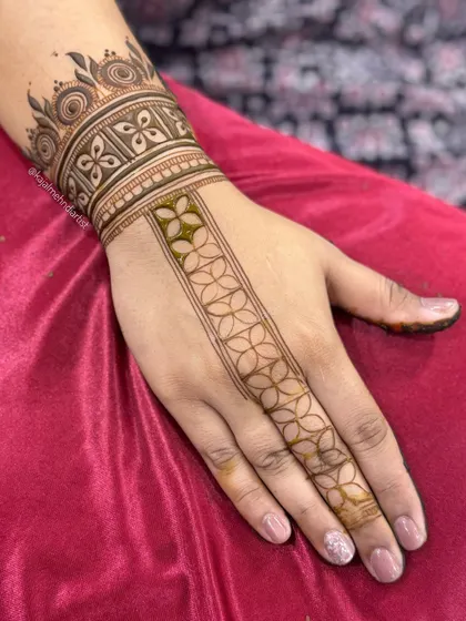 A simple and elegant henna strip for the groom's sister, showing the fresh henna paste.