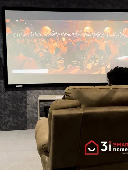 The view from the recliner in this compact theater, showing the large screen and the simple, effective AV setup.