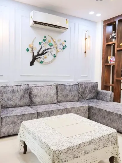 This living room from a completed project features a plush grey velvet sofa, elegant wall molding, and a striking tree-like metal wall art piece.