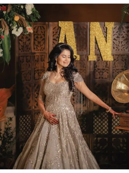 A beautiful solo portrait of the bride, Apoorva, at her Sangeet. Her elegant gown and serene expression are captured against a rustic, decorated backdrop.