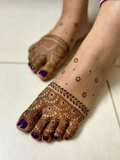 Simple yet elegant feet mehendi to accompany an engagement look, with detailed toe designs and scattered floral motifs.