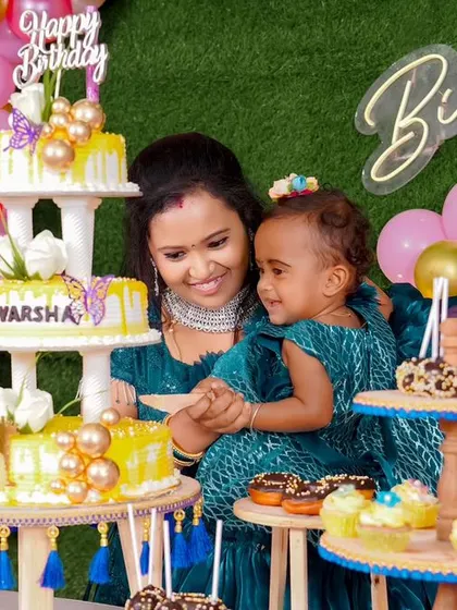 An elaborate dessert spread for a first birthday. Featuring a multi-tiered main cake, cupcakes, and other sweet treats, this setup ensures there's something delicious for every guest to enjoy.