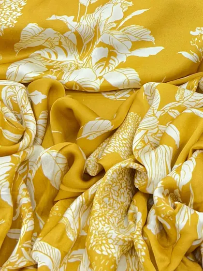 This mustard yellow modal satin with a bold white floral print is perfect for creating vibrant outfits. Its fluid drape is ideal for dresses, gowns, and co-ord sets.