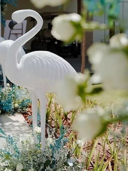 A close-up of the white flamingo statues used for our tropical-themed pool party. These elegant props stood amidst a bed of blue and white florals, perfectly capturing the chic paradise vibe.