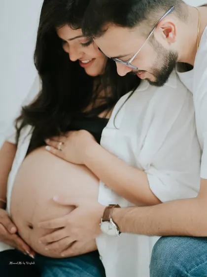 Both partners connecting with the baby bump. This studio portrait is a beautiful way to show the shared excitement and love for your little one.