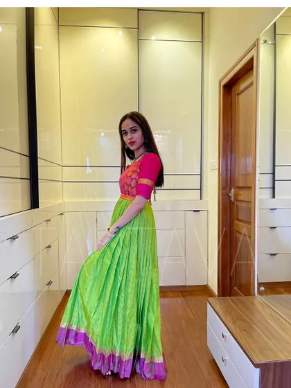 A side profile of the green and pink gown, showing how the pleats provide volume and grace. The contrasting brocade on the bodice adds another layer of detail.