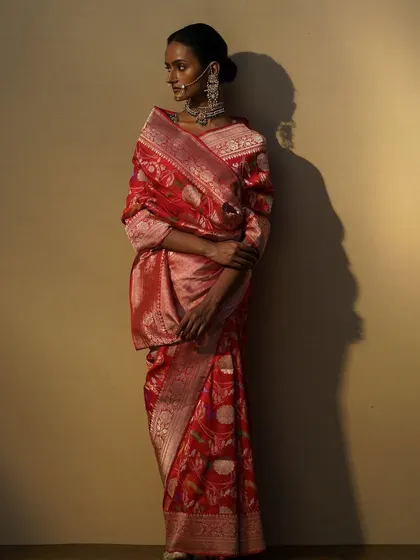 A side profile of the red Banarasi saree look, showing the intricate weave and the way the light catches the silk.