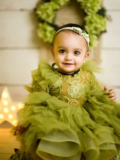 A close-up portrait from the first birthday session. Her sweet smile and the lovely details of her ruffled green dress are the focus of this beautiful shot.