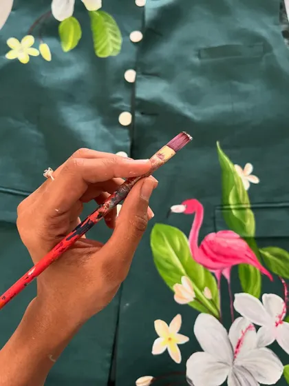 A close-up of me painting a flamingo on a dark green jacket. The tropical theme is one of my favorites to work on, as it allows for so much color and life.