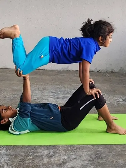 Two girls work together in this "flying" pose, demonstrating that strength and balance are skills for everyone to learn.