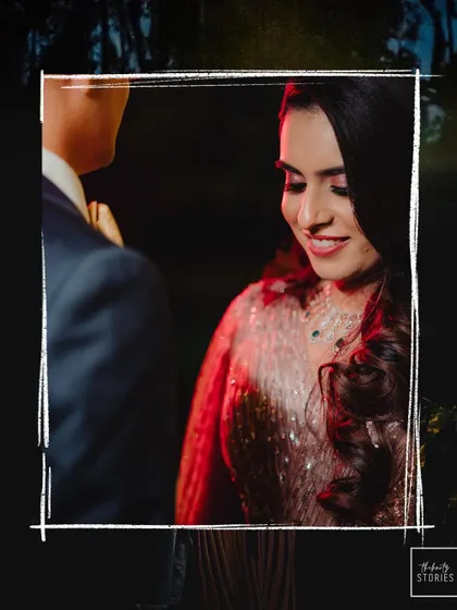 A close-up shot of the bride looking down with a gentle smile, as her partner stands beside her during an evening function.