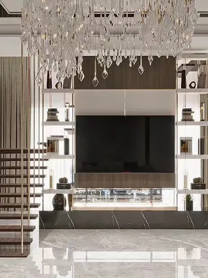 A grand living room in a duplex home, featuring a TV unit set against a marble base with a stunning crystal chandelier. The open staircase adds to the sense of scale and luxury.