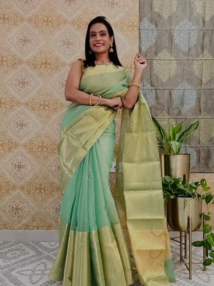 A beautiful pastel green tissue saree with a gold border. This is a very elegant and understated piece, perfect for a sophisticated look.