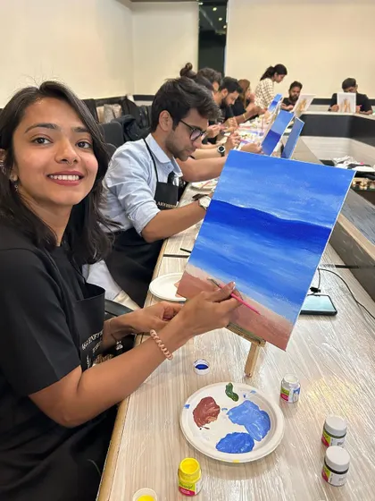 A participant looking up with a bright smile, clearly enjoying the painting process.