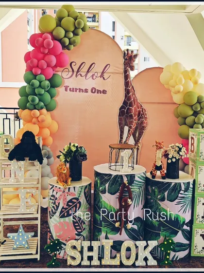 Shlok's first birthday roar was celebrated with this charming jungle theme. The decor features a tall giraffe cutout, monstera leaf-printed plinths, and a "BABY" block display, all tied together with a colorful balloon arrangement.